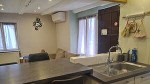 A compact kitchen with a sink, a dining table with chairs, and a window with curtains. - Riesling, Gites des Dix Vins (Dangolsheim)