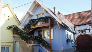 A two-story house with a wooden staircase, a balcony with greenery, and a red door. - Riesling, Gites des Dix Vins (Dangolsheim)