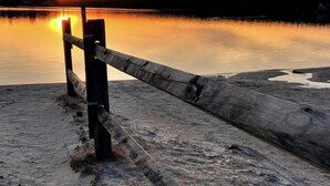 Een houten steiger die zich uitstrekt over kalm water bij zonsondergang.
