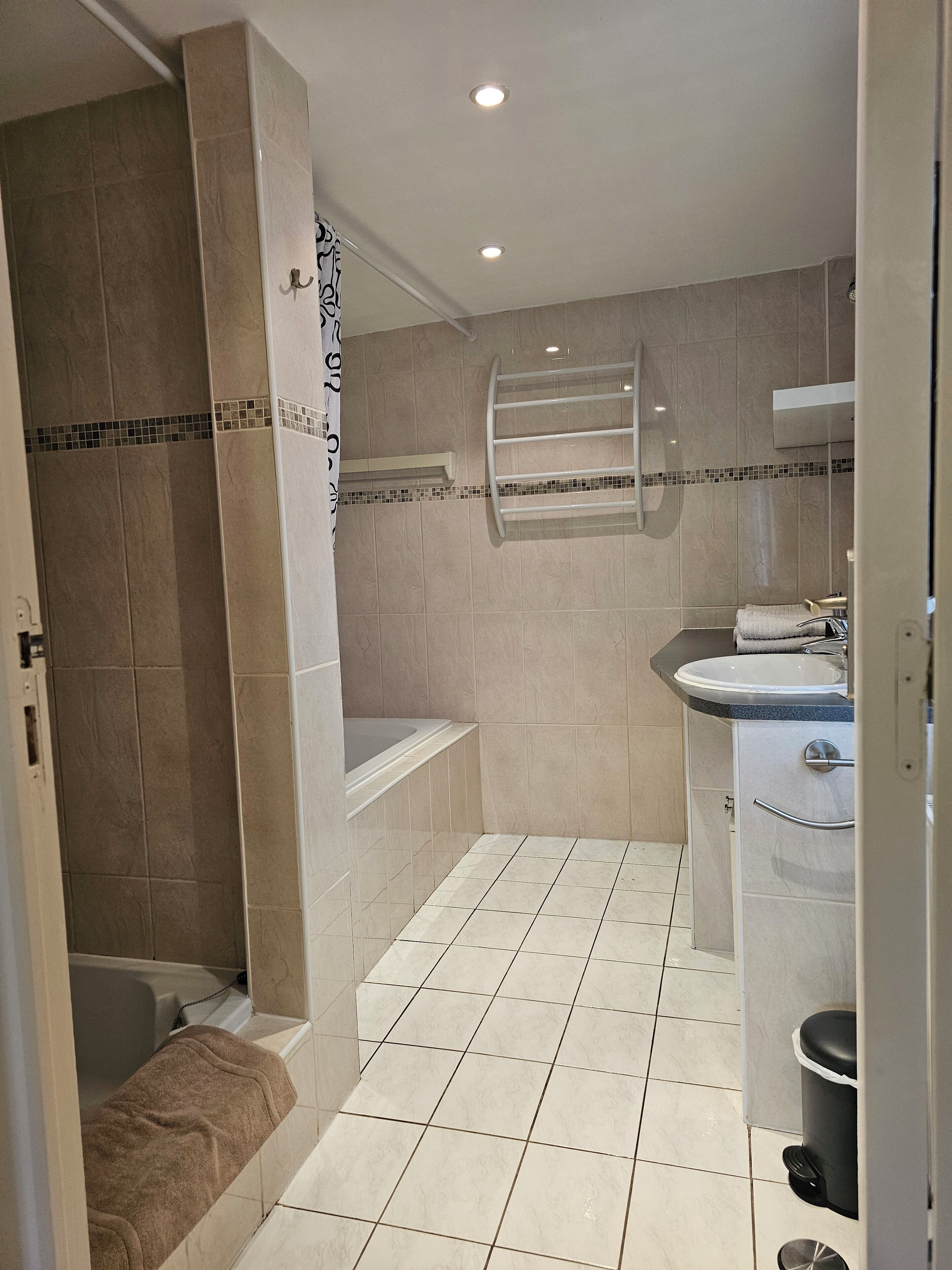 A bathroom with a bathtub, a shower, a sink, and a towel rack.