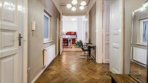 Un couloir doté d’un plancher en bois, de portes blanches et d’un coin repas à l’arrière-plan.