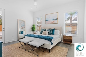 A bedroom with a bed, bedside tables, a mirror, and a window with blinds. - Ash in the Sand - Private Pool / Golf Cart / 6 Bikes / Game Room (Santa Rosa Beach)