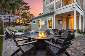 A patio with a fire pit, outdoor seating, and a pool.