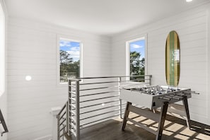 A room with a foosball table, a window, and a surfboard. - Ash in the Sand | 30A | Privte Pool | Golf Cart | Bikes | Games (Santa Rosa Beach)