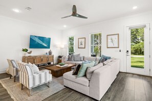 A modern living room with a sofa, armchairs, a coffee table, and a television.