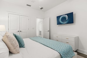 A bedroom with a bed, a dresser, a television on the wall, and a door. - Ash in the Sand | 30A | Privte Pool | Golf Cart | Bikes | Games (Santa Rosa Beach)