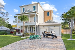 A two-story house with a garage, a driveway, and a golf cart parked in front. - Ash in the Sand | 30A | Privte Pool | Golf Cart | Bikes | Games (Santa Rosa Beach)