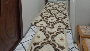Un corridoio con pavimento a motivi, porte in legno e un frigorifero sullo sfondo.