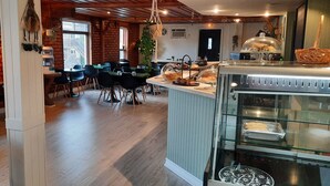 A cozy restaurant with a brick wall, wooden floors, and a central island with a glass display case. - KWE Café & Auberge (Pohenegamook)