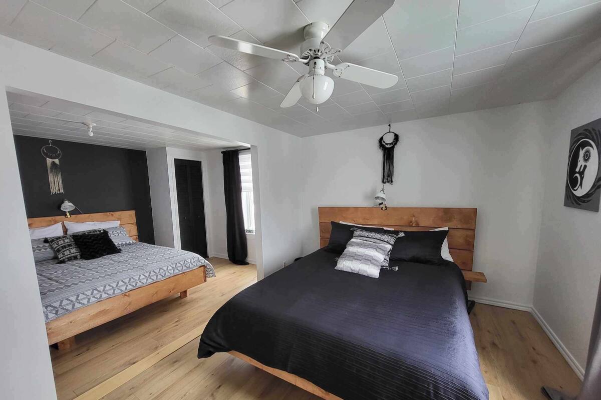 A bedroom with two beds, a ceiling fan, and a door leading to another room.