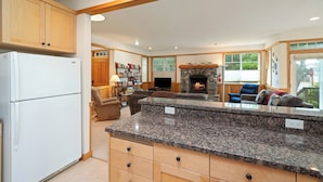 A spacious kitchen with granite countertops, wooden cabinets, and a built-in fireplace.