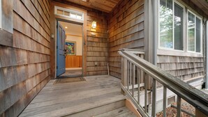 A wooden exterior with a porch, a blue door, and a number '115' sign.