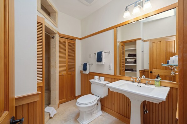 Un baño con inodoro blanco, tocador de madera y un espejo grande.