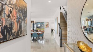 Un intérieur moderne comprenant un espace repas, un escalier et des œuvres d’art.