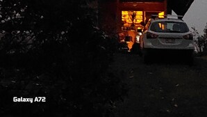 Una casa con un amplio ventanal y un coche estacionado en la entrada.