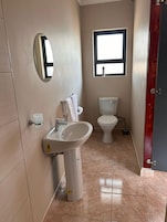 Ein Badezimmer mit Waschbecken, Spiegel, Toilette und Fenster.