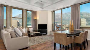 A spacious living room with a sofa, TV, and dining area, large windows with mountain views. - Cartwrights Corner 1403 (Cape Town)