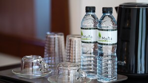 A tray with two bottles of Myna water, a glass pitcher, and a glass cup on a table. - Hill Myna Holiday Park & Cafe (Choeng Thale)
