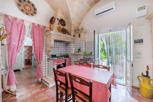 A kitchen with a red and white checkered tablecloth, a stove, and a sink.