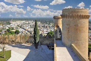 A historic stone tower with a paved courtyard and a view of a cityscape. - Carbone Country House Oria (Oria)