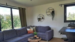 Ein modernes Wohnzimmer mit einem grauen Ecksofa, einem kleinen Holztisch und einem schwarzen Beistelltisch mit einem dekorativen Gegenstand.
