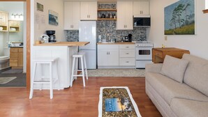 Una cocina compacta con armarios blancos, encimera de madera y salpicadero de azulejos.