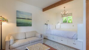Un dormitorio con una cama, un sofá, una mesita de noche, una lámpara y un cuadro.