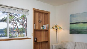 Una sala de estar con una estantería de madera, un sofá, una mesa y un cuadro en la pared.