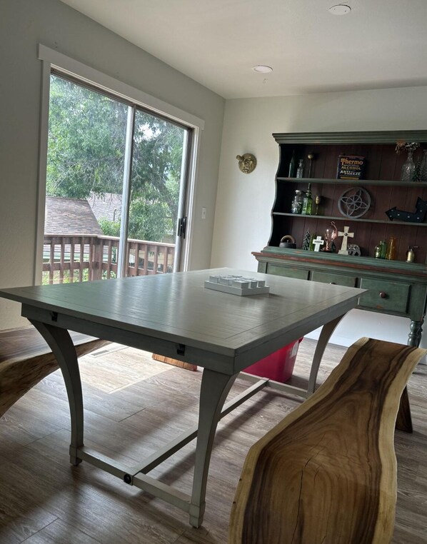 A dining area with a table, chairs, and a wooden cabinet with shelves.