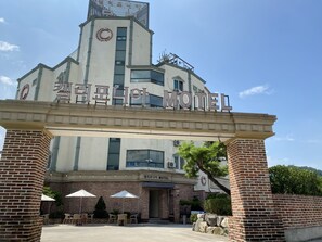 Un motel avec une enseigne bien visible, une façade en briques et un espace extérieur aménagé avec des sièges.