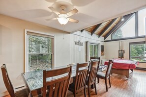 A dining area with wooden chairs and a glass table, large windows, and a ceiling fan. - Poconos Chalet Newly Renovated, Great Location 3 Bedroom Home by RedAwning (Tobyhanna)