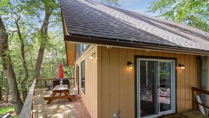 A wooden deck with a picnic table and chairs, a red umbrella, and a door with glass panels. - Poconos Chalet Newly Renovated, Great Location 3 Bedroom Home by RedAwning (Tobyhanna)