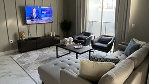 A modern living room with a large sofa, a coffee table, and a flat-screen TV mounted on the wall. - 1094ssp-the Retreat At Championsgate 4 Bedroom Home by RedAwning (Davenport)