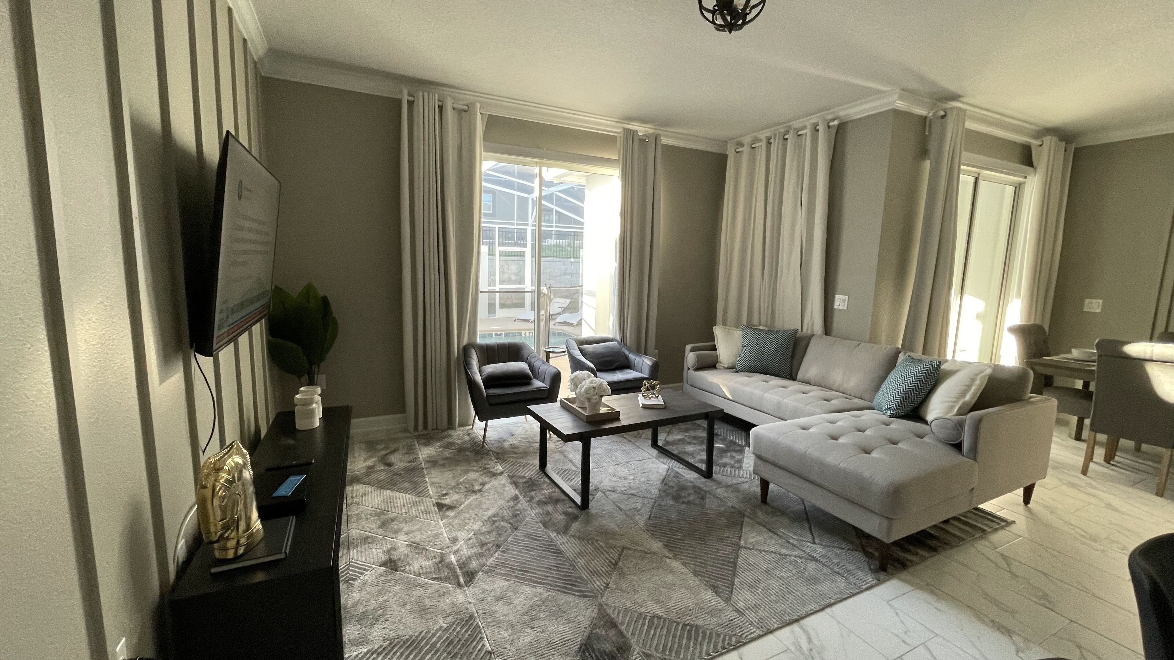 Una sala de estar moderna con un sofá, sillones, una mesa de centro y una televisión.