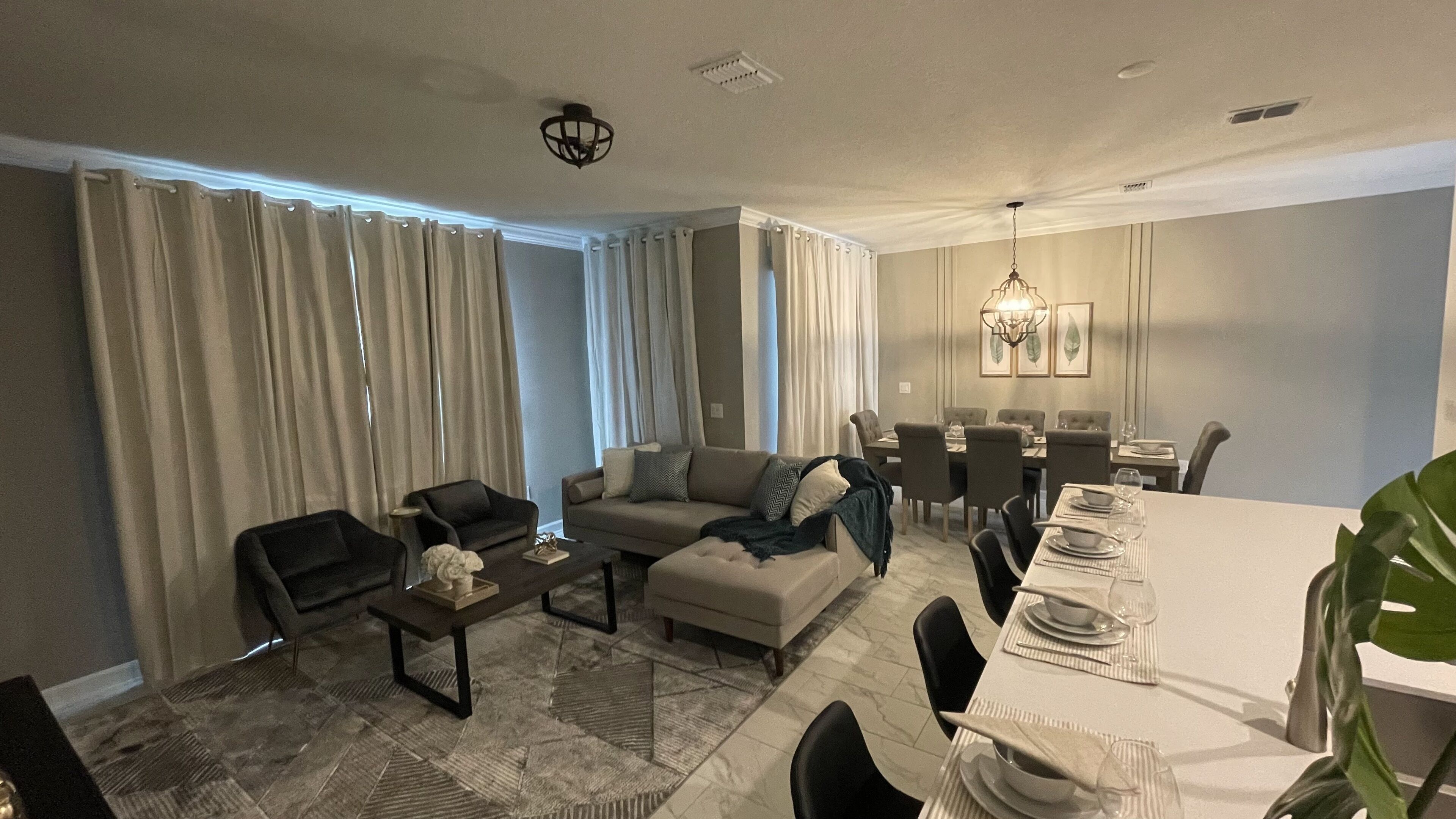 Un salon moderne avec un canapé, une table basse et un coin repas comprenant des chaises et une table dressée pour le dîner.