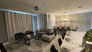 A modern living room with a sofa, coffee table, and dining area with chairs and a table set for a meal. - 1094ssp-the Retreat At Championsgate 4 Bedroom Home by RedAwning (Davenport)