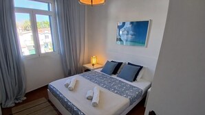A neatly made bed with towels, a bedside lamp, and a painting on the wall. - Sandybeachapartment1 in the Golden Island (Vila Baleira)