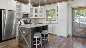 A modern kitchen with white cabinetry, stainless steel appliances, and a wooden ceiling. - Southern Honey in Hochatown/Broken Bow, OK (Broken Bow)