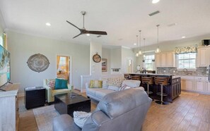 A spacious living room with a grey sofa, a coffee table, and a ceiling fan. - Welcome Beach Bum Inn (Panama City Beach)