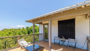 Una terraza techada al aire libre con mobiliario de mimbre, una mesa y una parrilla.