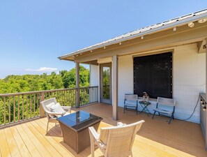 A covered outdoor deck with wicker furniture, a table, and a grill. - Welcome Beach Bum Inn (Panama City Beach)