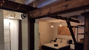 Un dormitorio con una cama, una escalera de madera y un estante fijado a la pared.