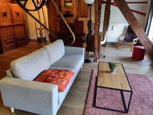 A modern living room with a grey sofa, a wooden coffee table, and a red ottoman.