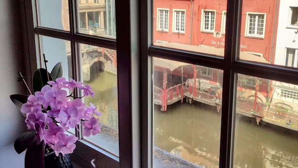 Una ventana con vistas a un canal y edificios con fachadas rojas y blancas.
