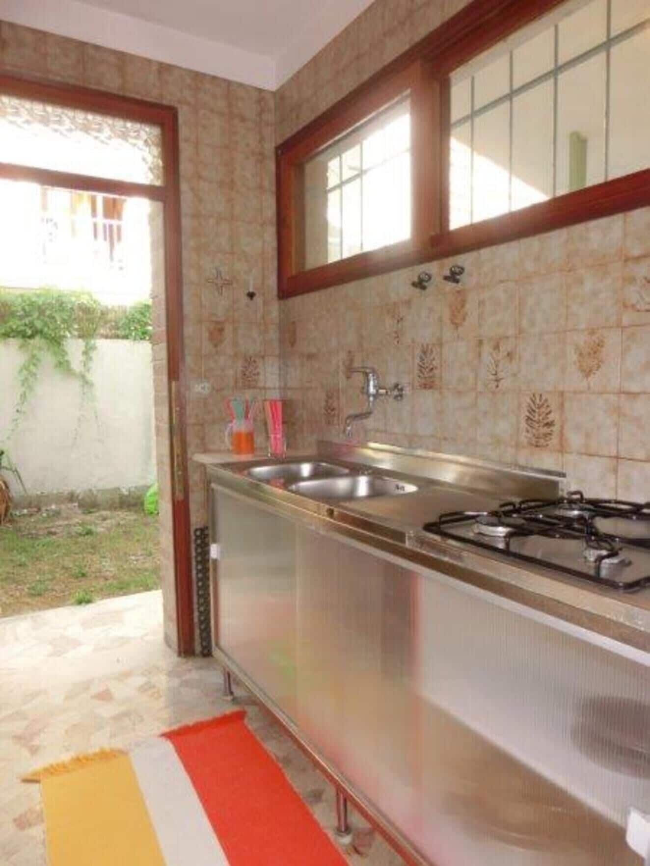 A kitchen with a stainless steel sink, a gas stove, and a window above the sink.