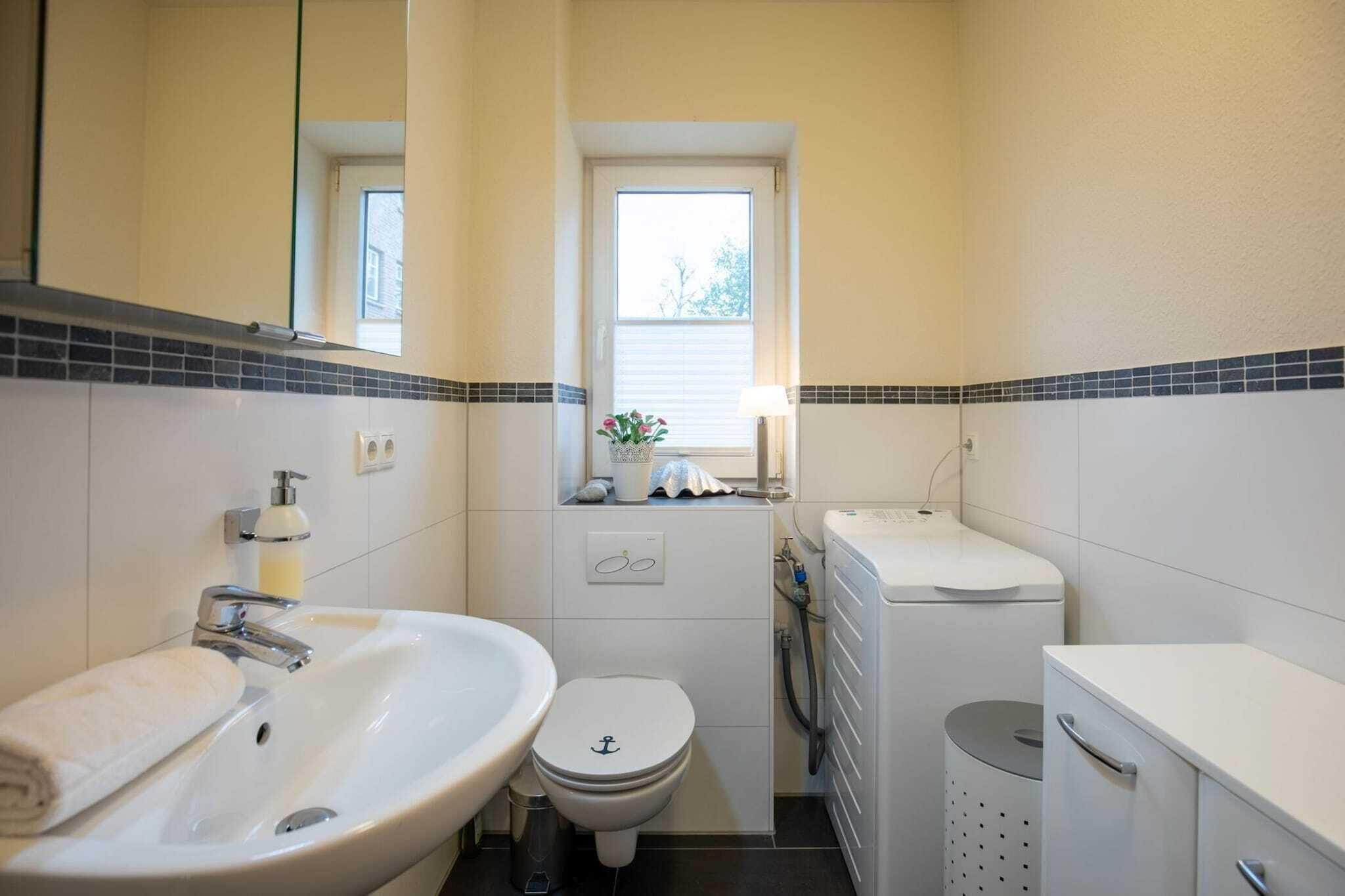 A small bathroom with a sink, toilet, and a window above the toilet.
