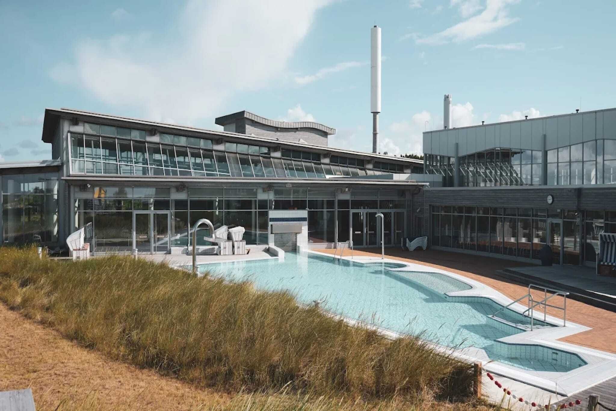 Un bâtiment moderne doté d’une piscine et d’un espace extérieur aménagé pour se détendre.