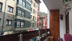 Uma varanda com vista para edifícios altos, uma porta de madeira e um pequeno banquinho.