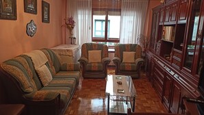 Uma sala de estar com sofá, duas poltronas, mesa de centro e um armário.