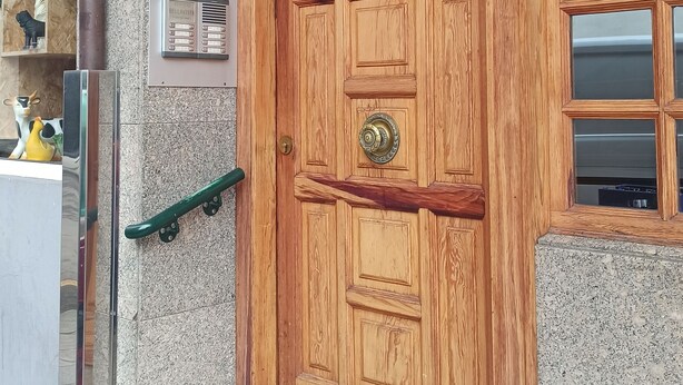 Uma porta de madeira com puxador de metal e uma pequena janela acima.